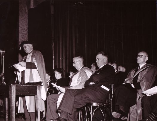 Conferring of ANU degrees at Albert Hall. Sir John Medley speaking, Mrs Chifley, George Currie and others seated.