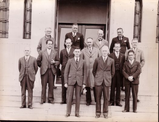 Group of men, mostly journalists, on the steps of the Institute of Anatomy. CS Daley at front.