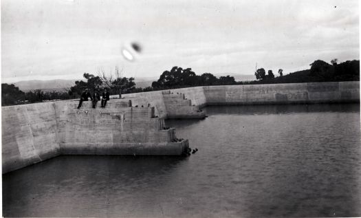 Reservoir on Black Mountain with three men sitting on the concrete wall of the dam.