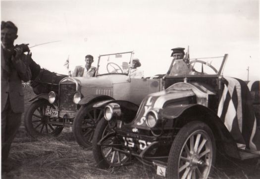 Percy Jolley at the wheel of a T-model Ford.  Frank Jolley standing by veteran car. Another veteran car is in the foreground with unknown man standing at left.