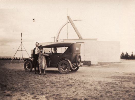 Model T Ford at Mt Stromlo. An unidentified man and woman are standing next to the car and a girl is in the car.