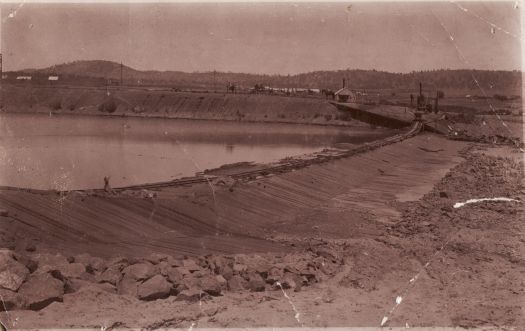 Narrow gauge rail line across a dam.