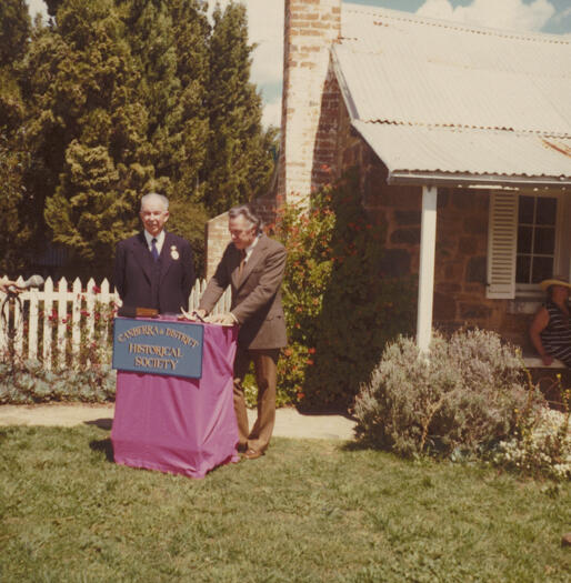 John Cumpston, president of the CDHS, paying the peppercorn rental for Blundell's Cottage to Colin Davis from the Department of the Capital Territory