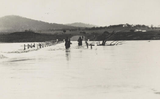 Workmen removing bridge rails and flood debris from Scotts Crossing over the flooded Molonglo River