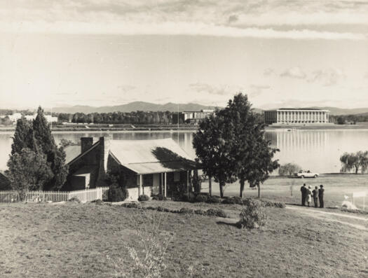Four people looking at the view from Blundells Cottage across Lake Burley Griffin to the National Library
