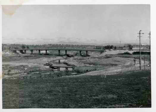 Construction of Lake Burley Griffin from Regatta Point. Shows the lake wall on the south shore, Parliament House and the Administration Building (John Gorton Building).