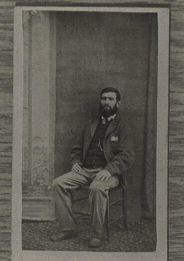 Man sitting on chair in studio. Reverse stamped 'A.M. Salomon, artist and photographer.'