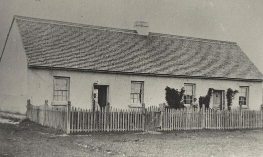 Two cottages with a woman standing outside each one.