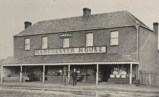 Two storey brick building with verandah. Two men standing outside - one possibly Robert Sindell.