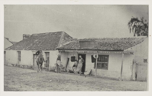 Shows William Brook and assistant standing outside their modest shop. Also man on horse - satisfied customer?