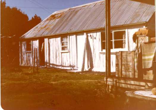 Side view of Ted Tong's slab house at Upper Naas. A man is standing in the doorway.