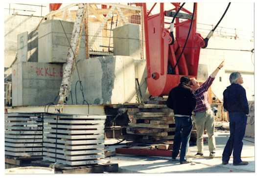 Three workmen looking up at a crane